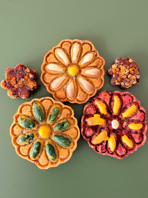 Floral-shaped cookies with colorful icing on a green background